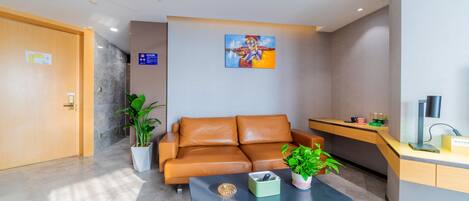 A modern lobby with a leather sofa, a coffee table, a desk, and a painting on the wall.