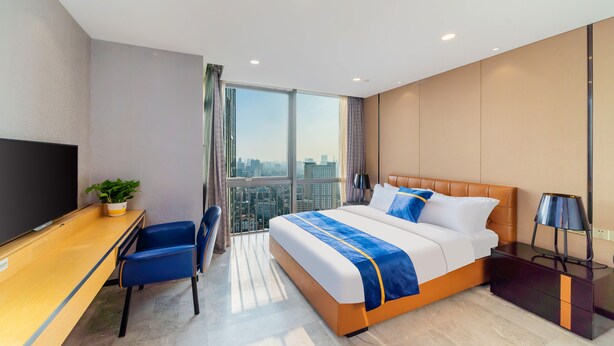 A modern hotel room with a large bed, a desk, and a TV. - Cloudy International Apartment (Guangzhou)