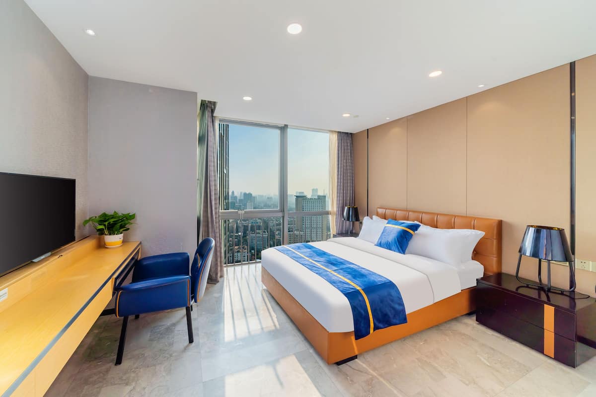 Quarto de hotel moderno com uma cama grande, uma mesa e uma televisão.