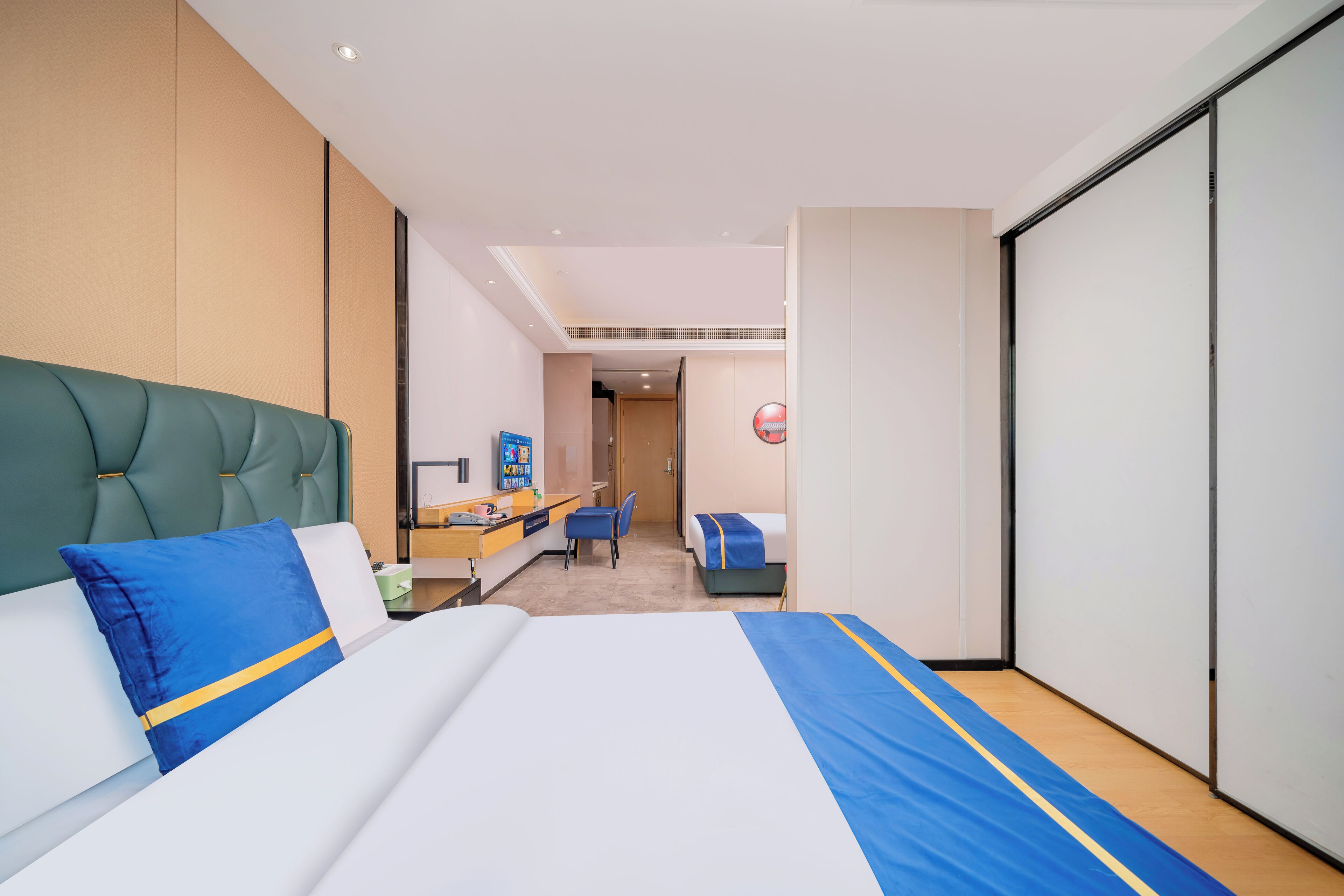A modern hotel room with a large bed, a desk, and a wardrobe.