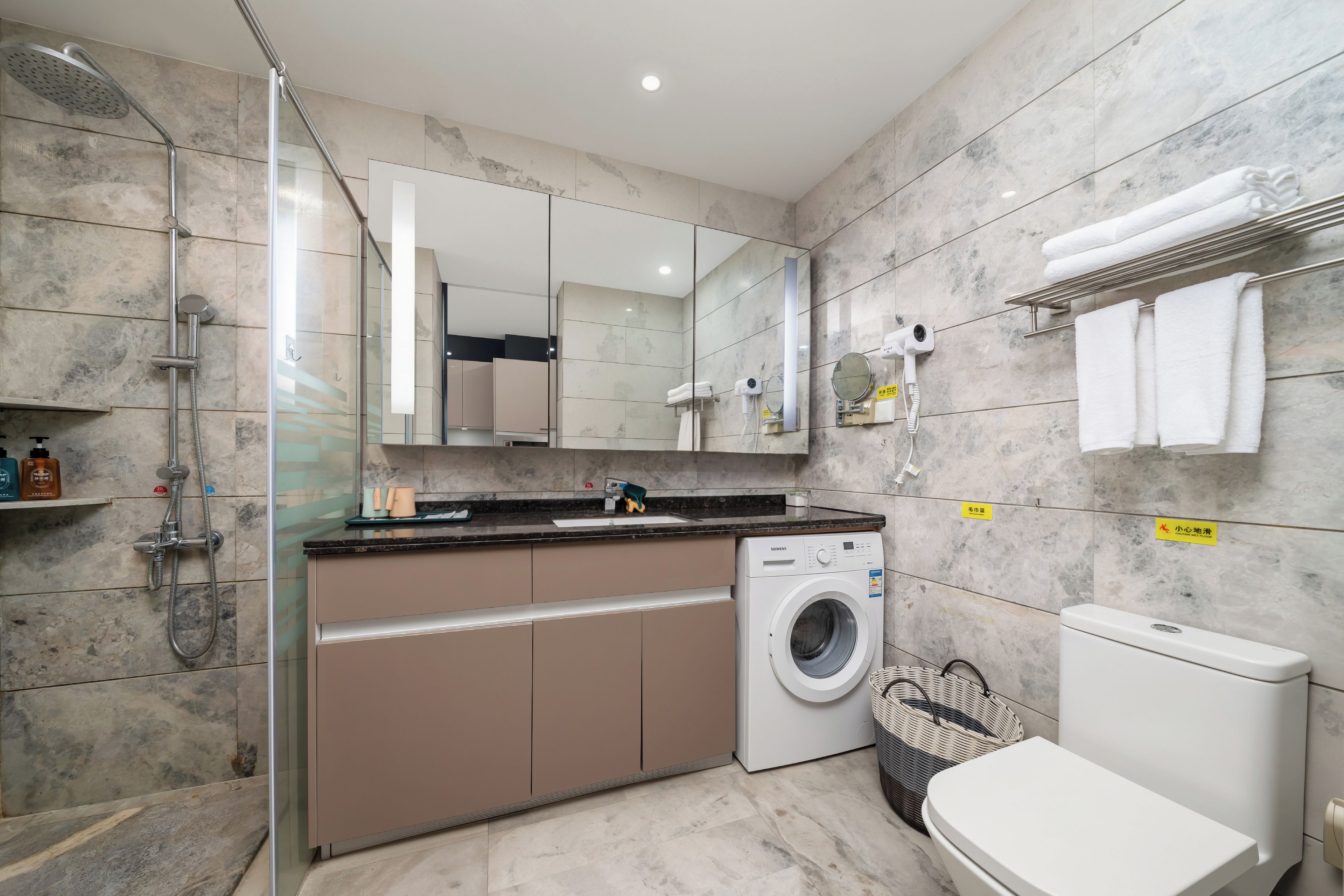 A modern bathroom with a shower, a washing machine, and a toilet.