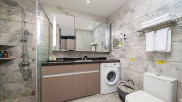 A modern bathroom with a shower, a washing machine, and a toilet.
