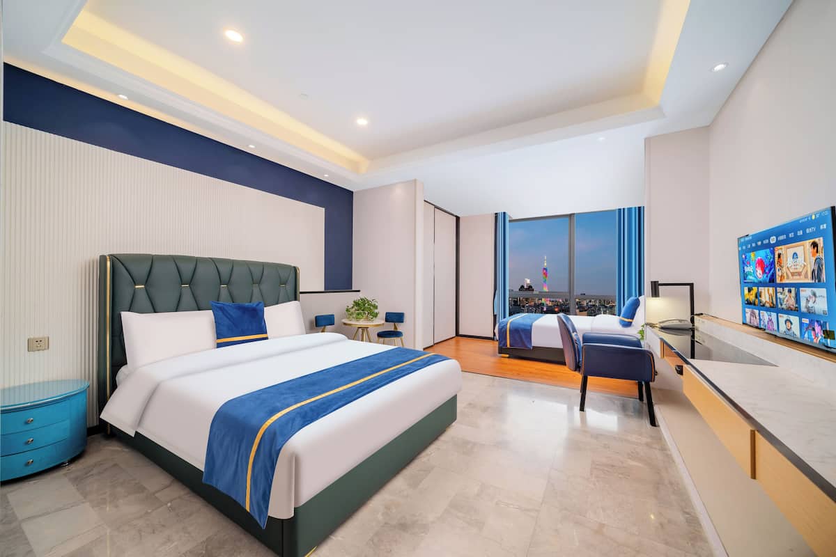 Quarto de hotel moderno com uma cama grande, uma mesa e vista para a cidade.