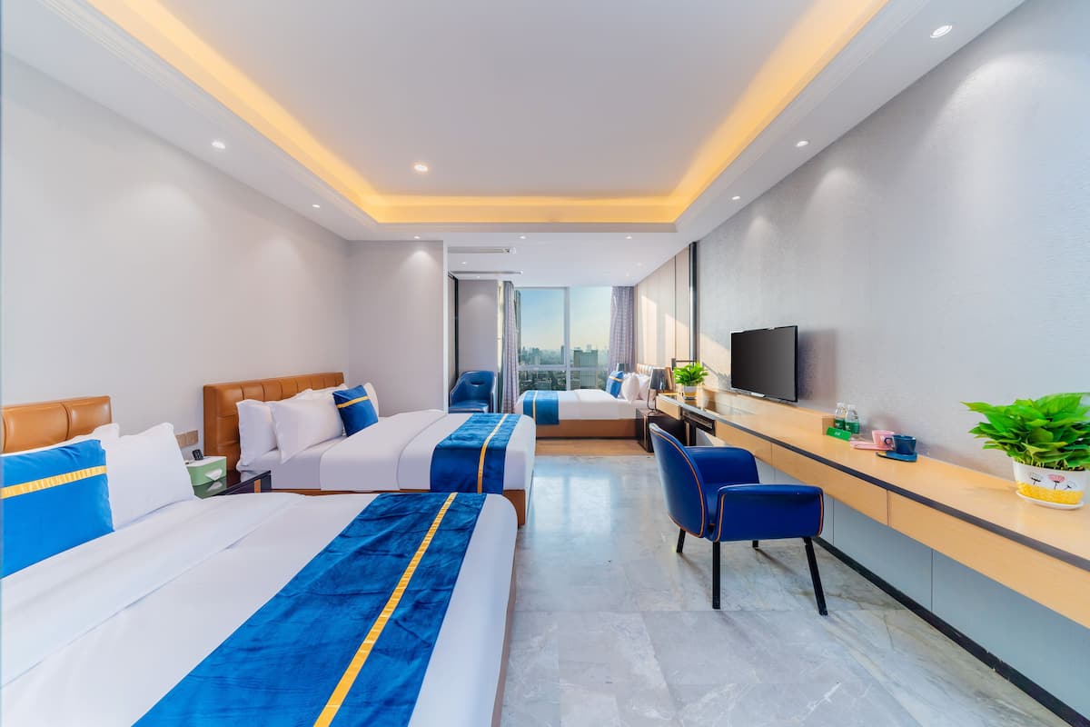 Quarto de hotel moderno com duas camas, uma mesa, uma televisão e vista para a cidade.