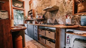 A rustic kitchen with stone walls, wooden cabinets, and a built-in stove. - CIRQUE 5 -  Two bedroom alpine lodge (Merrijig)