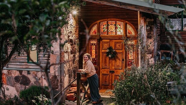 A rustic wooden house with a stone facade, a wooden door with stained glass, and a person standing by the entrance. - CIRQUE 5 -  Two bedroom alpine lodge (Merrijig)