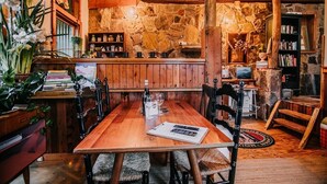 A cozy dining area with a wooden table and chairs, surrounded by stone walls and wooden beams. - CIRQUE 5 -  Two bedroom alpine lodge (Merrijig)
