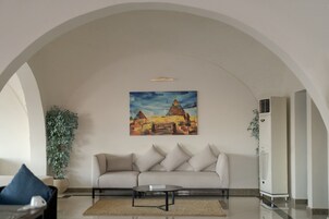 Una sala de estar con un sofá color beige, una mesa de centro y un cuadro de pirámides.