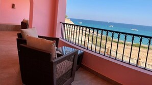 Un balcon doté de meubles en osier et offrant une vue sur la plage et l’océan.