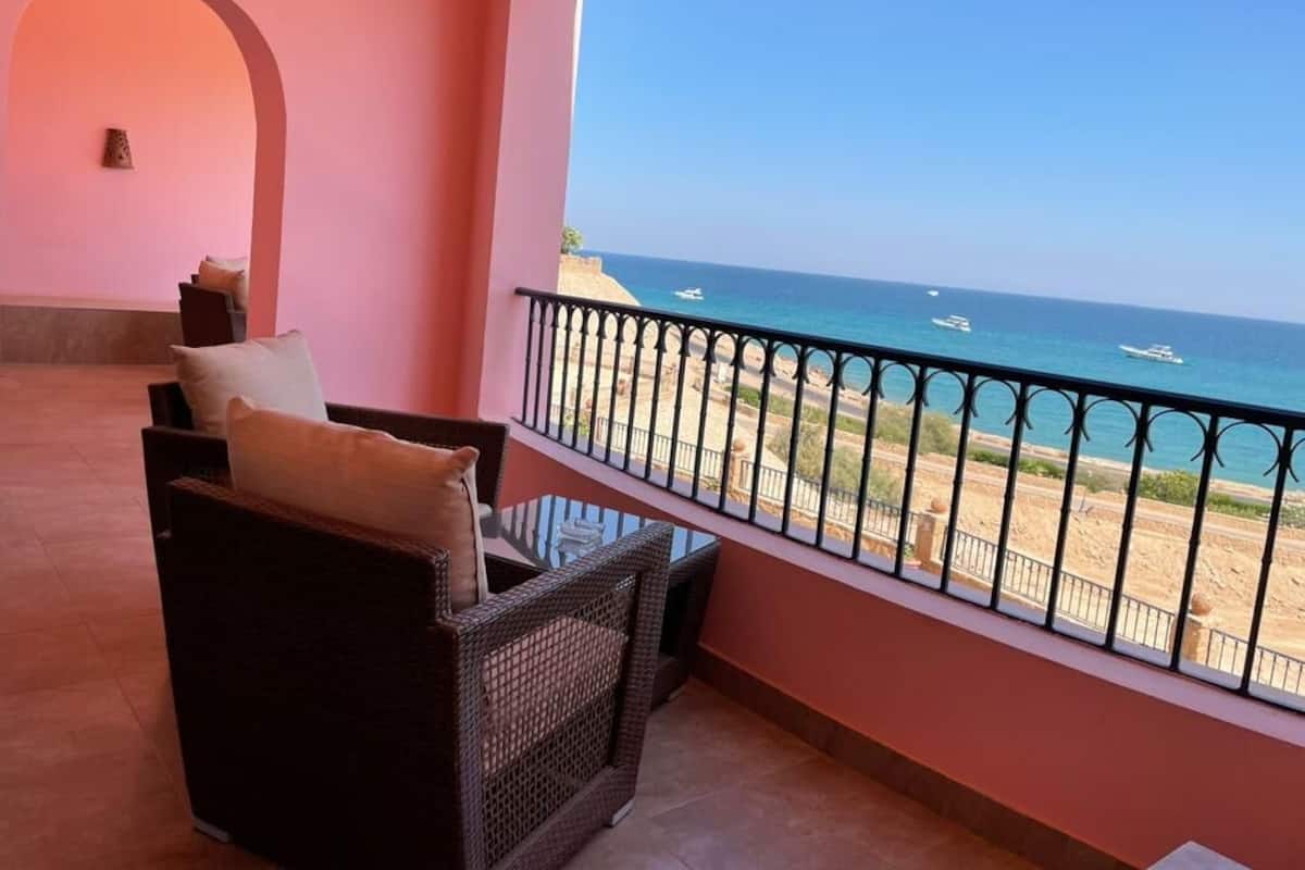 Un balcon doté de meubles en osier et offrant une vue sur la plage et l’océan.