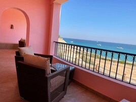 Un balcón con muebles de mimbre y vista a la playa y al océano.