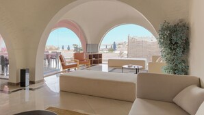 Un vaste espace de vie comprenant un grand canapé, un téléviseur et un coin repas avec des tables et des chaises.