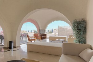 Amplia sala de estar con un sofá grande, televisor y comedor con mesas y sillas.