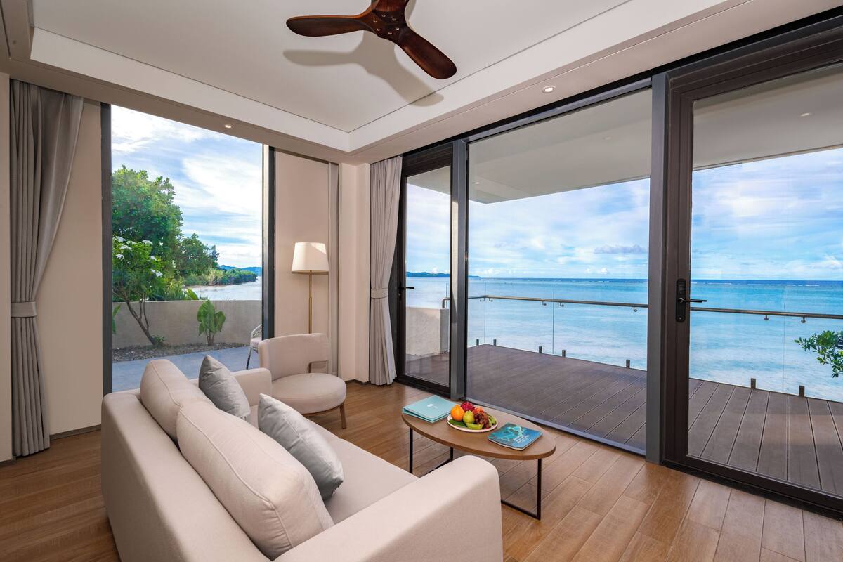 Ein modernes Wohnzimmer mit Sofa, Couchtisch und Meerblick durch große Schiebetüren.
