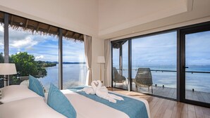 Een hotelkamer met een groot bed, een balkon met uitzicht op zee en een stoel.