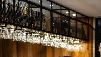 Zona de bar con mostradores de madera, taburetes de cuero y una lámpara colgante.