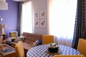 A cozy living room with a sofa, chairs, a coffee table, and framed artwork on the wall.