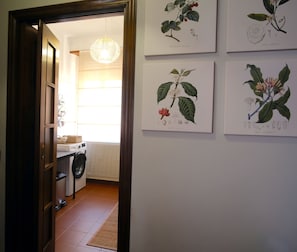 A hallway with a laundry area, a radiator, and a hanging light fixture.