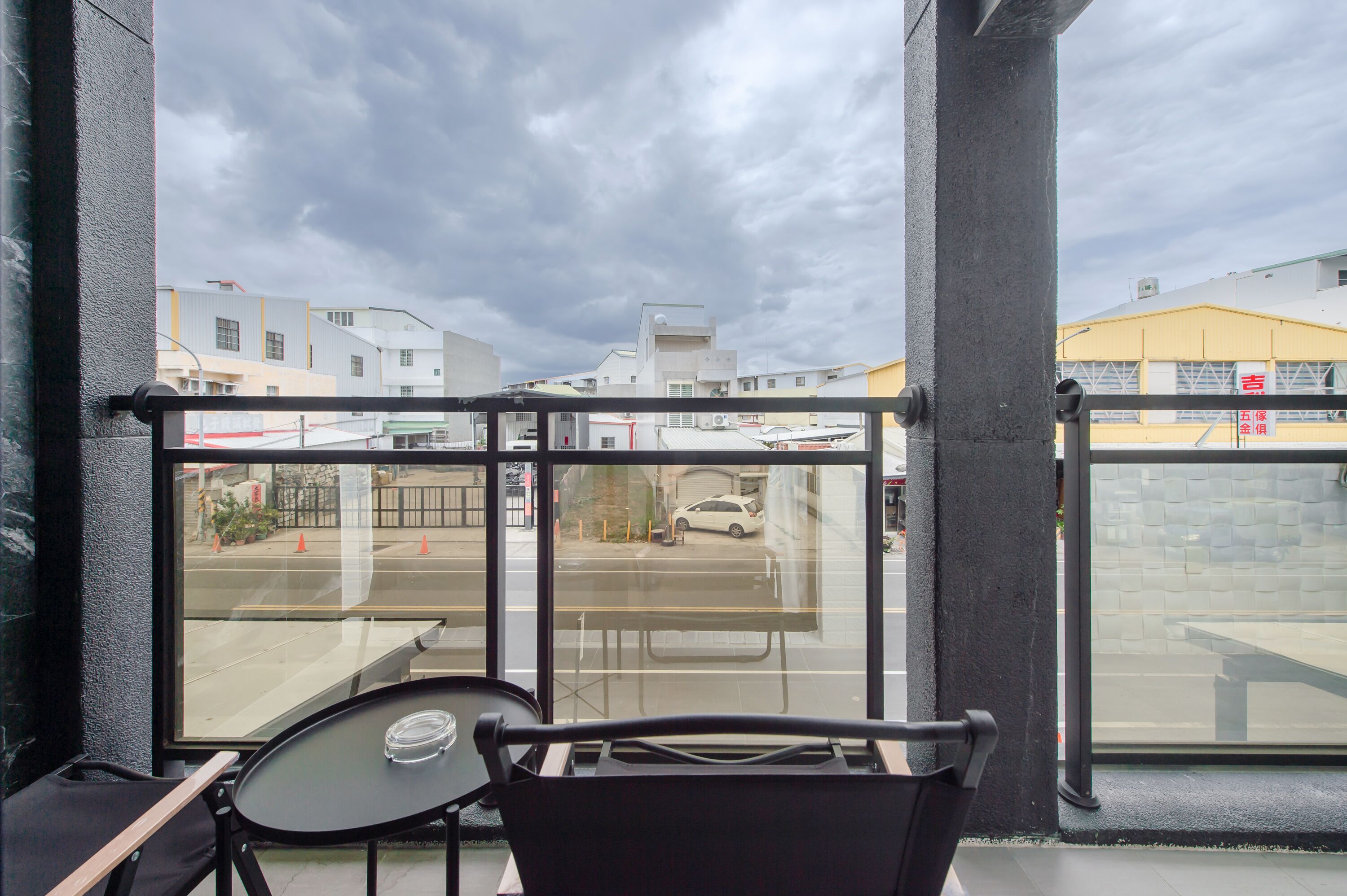 A balcony with a view of a parking lot and buildings.