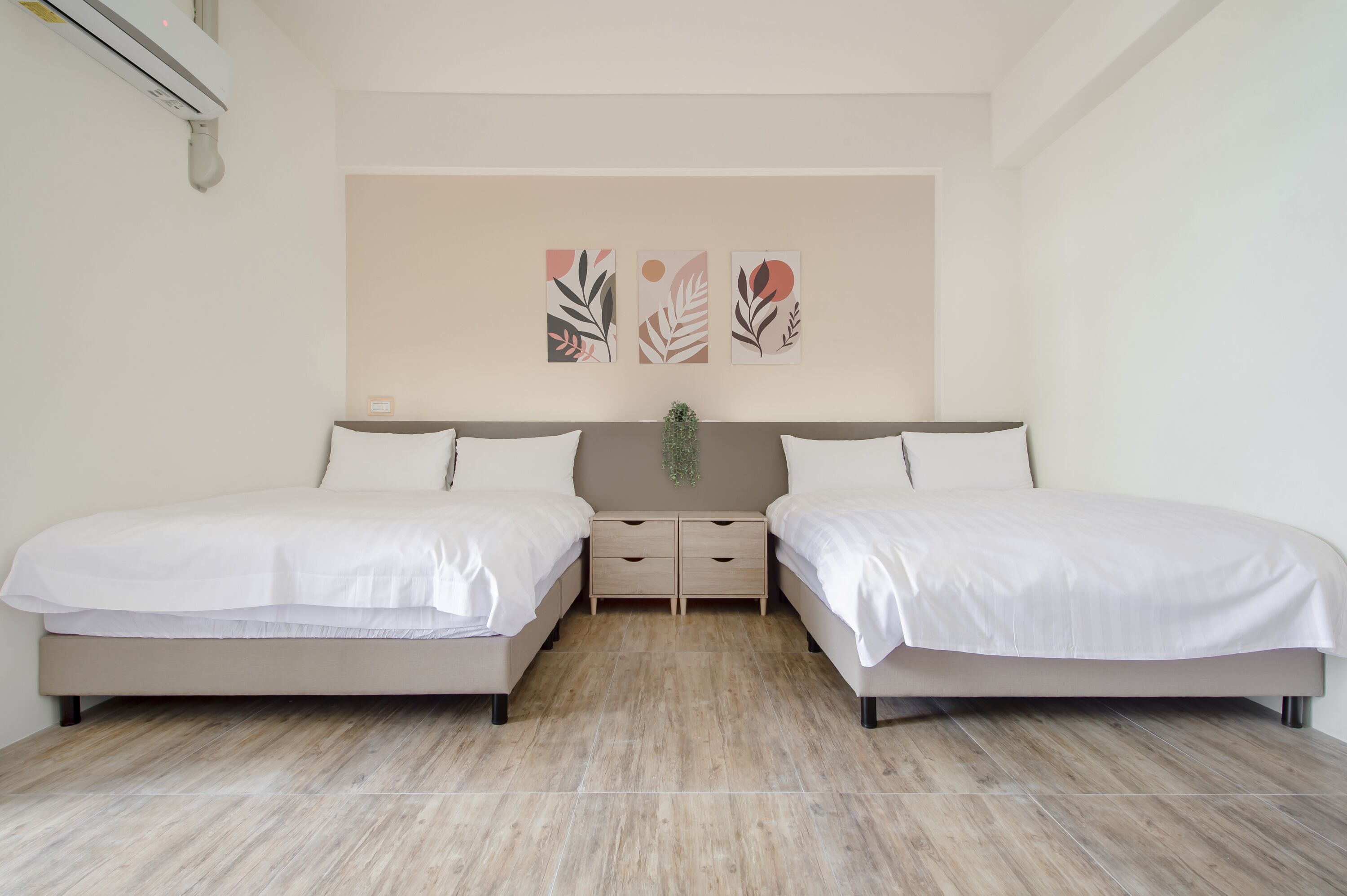 A bedroom with two beds, a neutral color scheme, and a wall-mounted air conditioner.