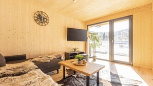 A modern living room with wooden walls, a sofa, a coffee table, and a TV mounted on the wall.
