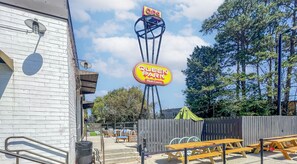 A Queen Park Multi-Cinema with a sign, outdoor seating, and a wooden fence.