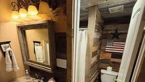 A rustic bathroom with a wooden vanity, a mirror, a sink, and a toilet. - Kaitlins Kottage at Serenity Hills Zion (Glendale)