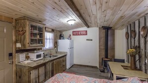 A rustic retreat with a wooden ceiling, a kitchen with a microwave, and a sign reading "Rustic Retreats". - Kaitlins Kottage at Serenity Hills Zion (Glendale)