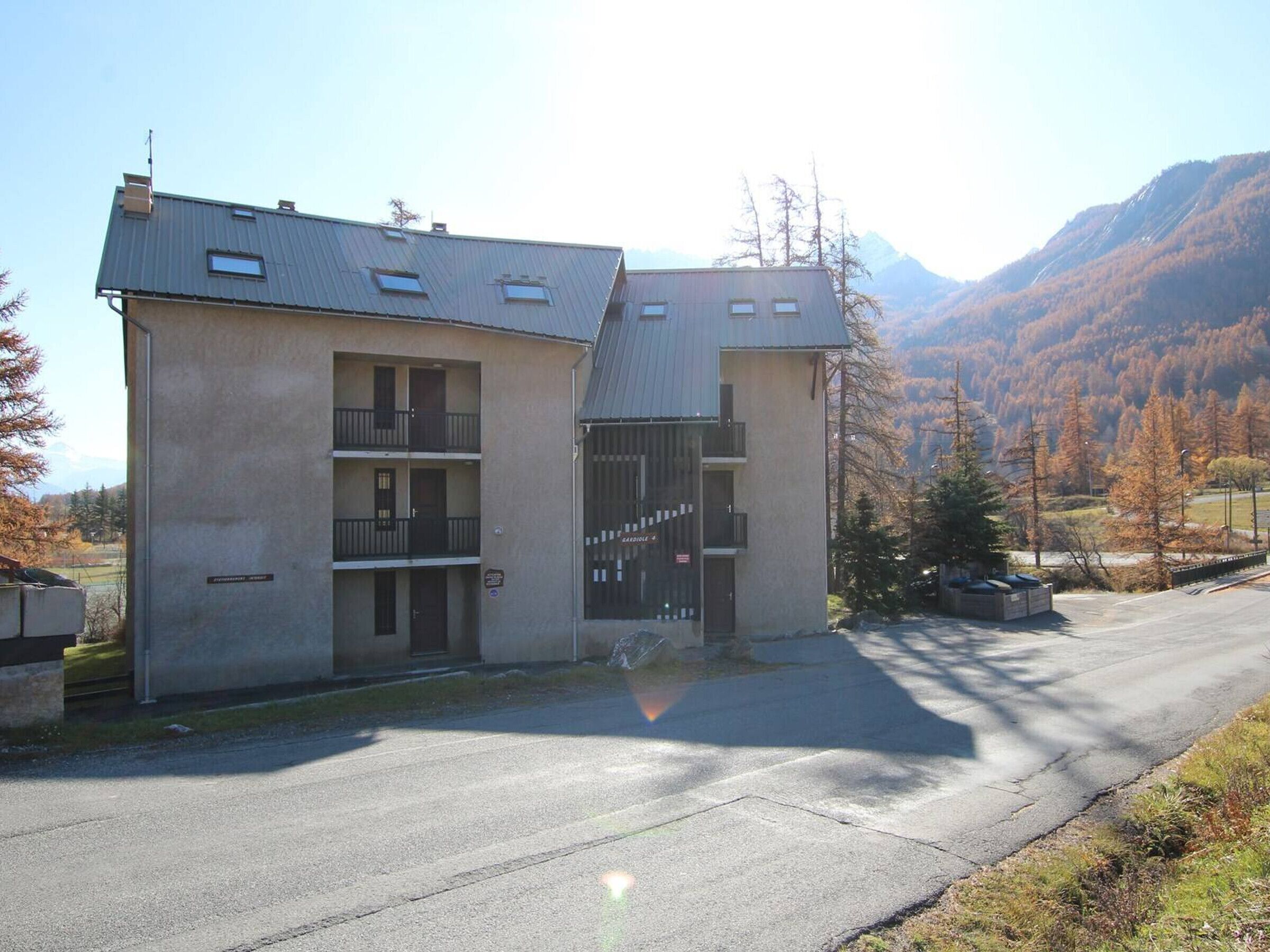 A two-story building with a balcony on the ground floor and a garage entrance.