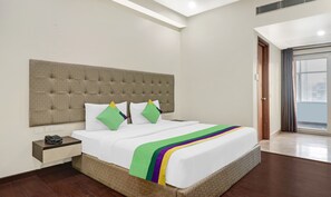 A hotel room with a large bed, a bedside table with a telephone, and a view of the city through a large window. - Hotel the Archer (Gurugram)