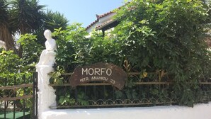 Una pared blanca con una reja metálica y un letrero que dice 'MORFO MTR. ANANJOU 23'.