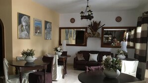 Un comedor con mesas redondas, sillas y un sofá.
