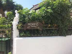 Una pared blanca con una reja metálica y un letrero que dice 'MORFO MTR. ANANJOU 23'.