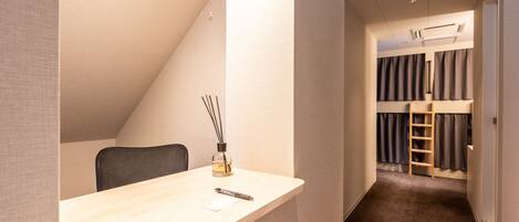 A modern, compact room with a desk, chair, and a bunk bed with a ladder.