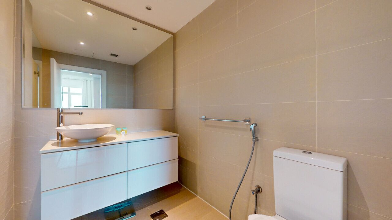 A modern bathroom with a white vanity, a large mirror, and a toilet.