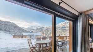 Ein Zimmer mit einem großen Fenster mit Blick auf eine verschneite Landschaft und Berge.