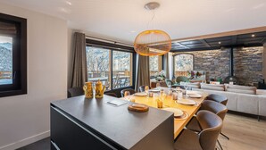 Ein moderner Essbereich mit einem großen Tisch für sechs Personen, einer Bar und einer Wand mit Steinverkleidung.