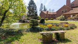 Ein Innenhof mit Teich, ordentlich geschnittenen Hecken und einer Steinsitzbank.