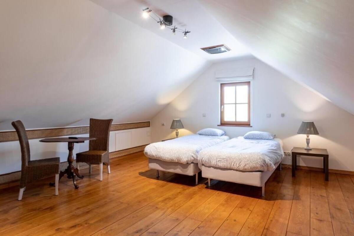 Un dormitorio con techo tipo loft, una cama, dos mesitas de noche, una silla y una pequeña mesa.