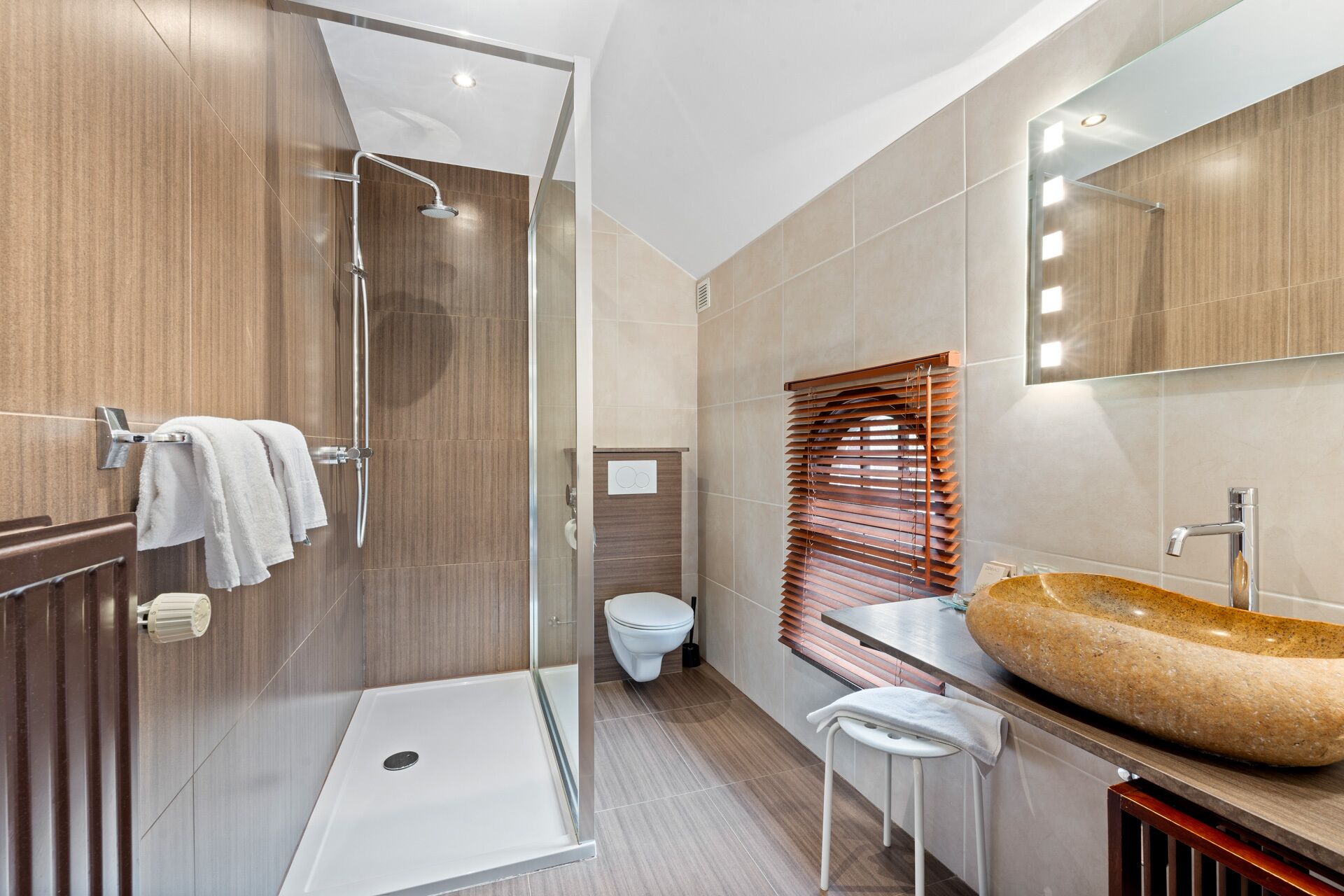 Un baño moderno con cabina de ducha de vidrio, tocador de madera con un lavabo grande y un inodoro con función bidé.