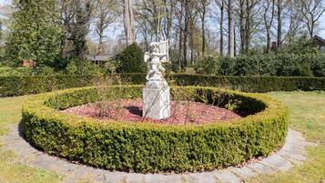 Um jardim circular com uma estátua central rodeada por sebes bem aparadas.