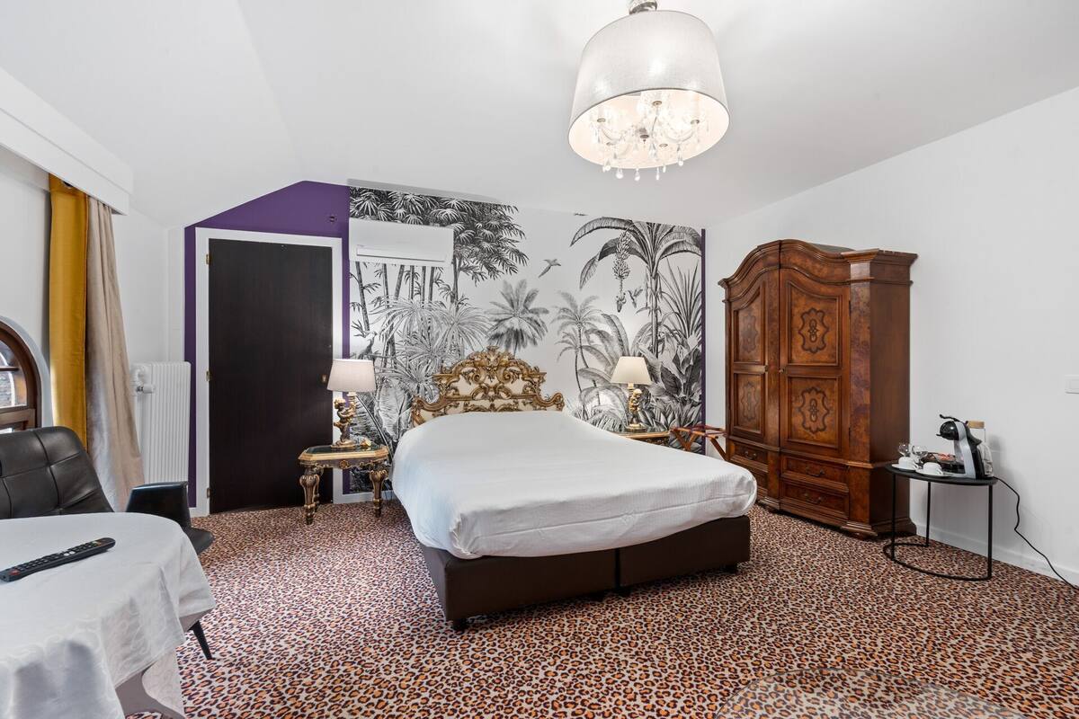 Un dormitorio con cama, armario, mesita de noche, lámpara y alfombra de estampado de leopardo.