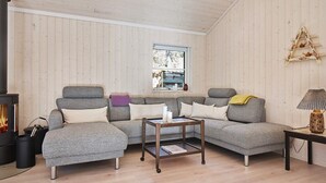 A cozy living room with a grey sectional sofa, a small wooden coffee table, and a fireplace. - 8 Person Holiday Home in Nexo (Nexø)