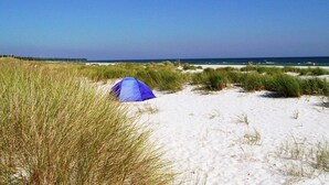 A beach scene with a blue tent on the sand, surrounded by grass and dunes. - 8 Person Holiday Home in Nexo (Nexø)