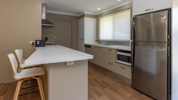 A compact kitchen with a built-in island, stainless steel appliances, and wooden flooring.