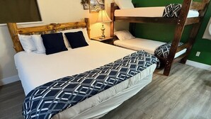 Een stapelbed met een bedsprei met patroon, een bedlampje en een groene muur.