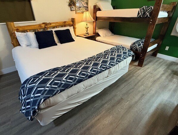 A bunk bed with a patterned bedspread, a bedside lamp, and a green wall.