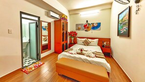 A hotel room with a bed, a wardrobe, a mirror, a nightstand, and a painting on the wall. - HANZ Cao Gia Hai Hotel (Ho Chi Minh City)
