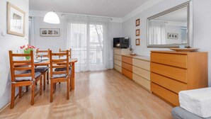 Una habitación con una mesa de comedor, sillas, un televisor, un aparador y una cama.