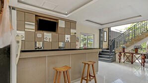 A modern kitchen with a bar area, wooden stools, and a staircase leading to an outdoor area. - Kiki Residence Bali (Denpasar)